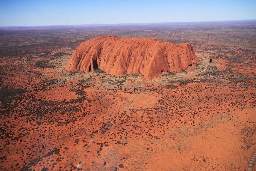 Aerial shot of Uluru - Ayers Rock surrounded by red earth - one of the best places to visit in Australia