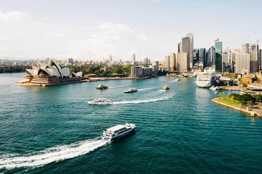 Sydney Harbour at golden hour with a boat sailing towards the harbour and smaller boats sitting in front of the Opera House