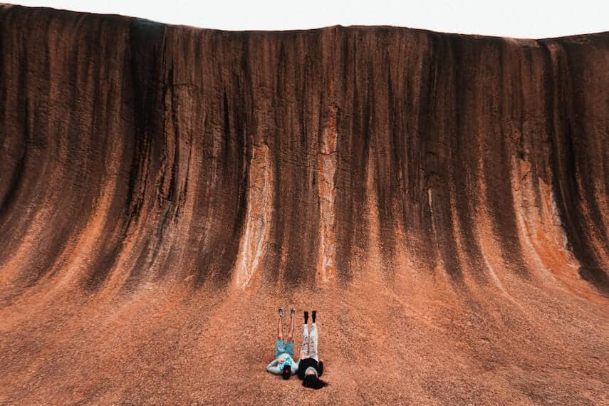 Couple lying at the base of Wave Rock, WA