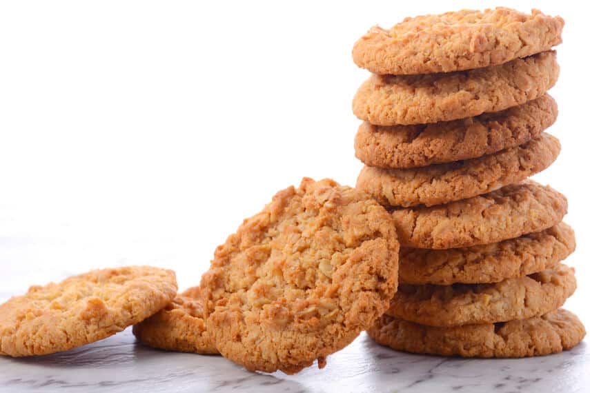 A pile of Anzac biscuits in a pile with three next to the pile