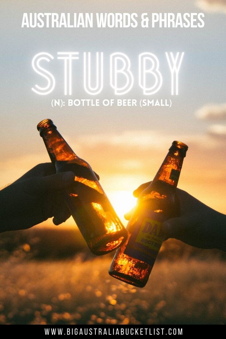 Australian Slang - Stubby = A small Bottle of Beer (featuring two hands holding beer bottles cheers-ing in a field in front of a sunset with text overlay of the translation)