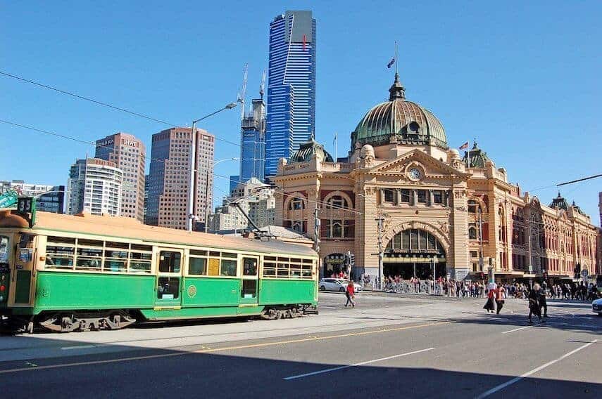 Green and yellow city circle tram in front of the yellow heritage listed domed building of Flinders Street Station