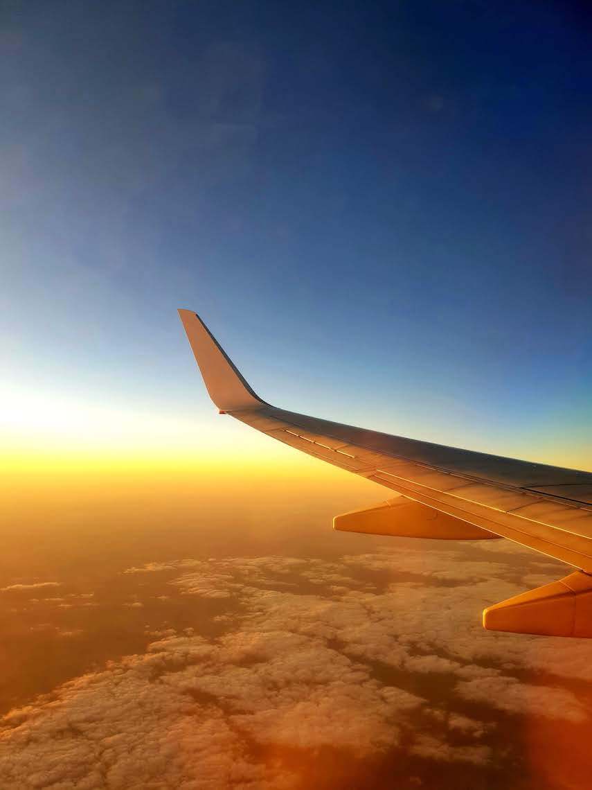 An airplane wing in the sky at sunset