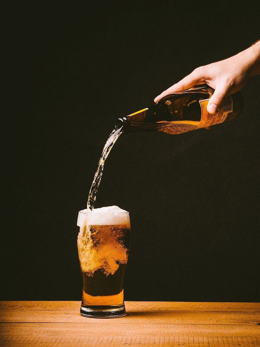 Hand pouring a pint of beer from a bottle