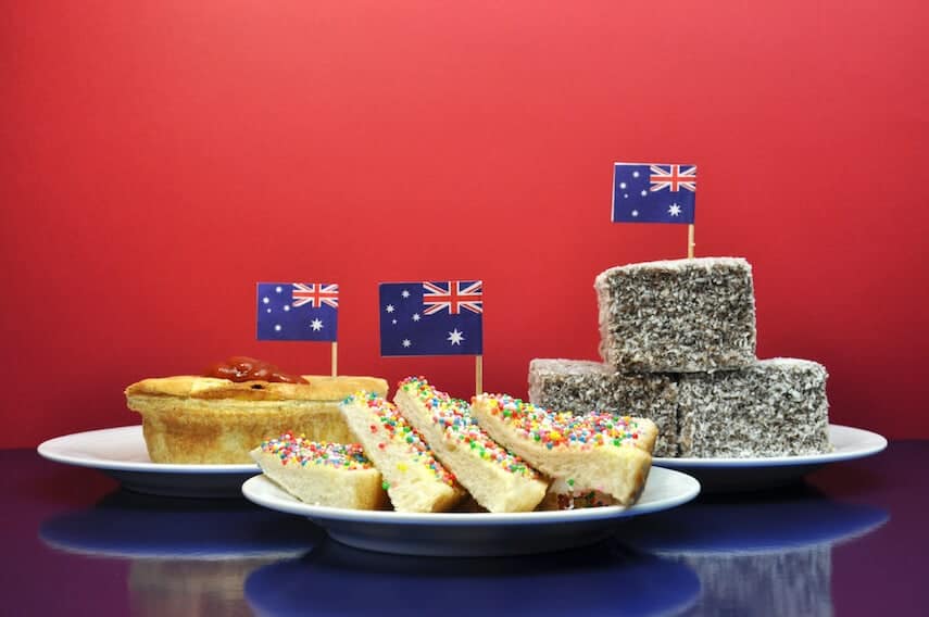 Iconic Australian Food (pie, lamington, fairy bread on plates topped with a miniature Australian flag)