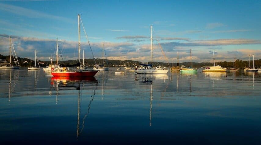 Lake Macquarie with still water and dotted with sail boats with coloured hulls