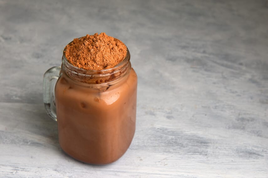 Milo and milk mix in a mason jar, topped with a pile of unmixed milo powder