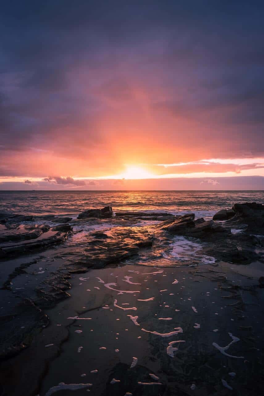 Sunrise at Mooloolaba Beach with flat rocks in the foreground