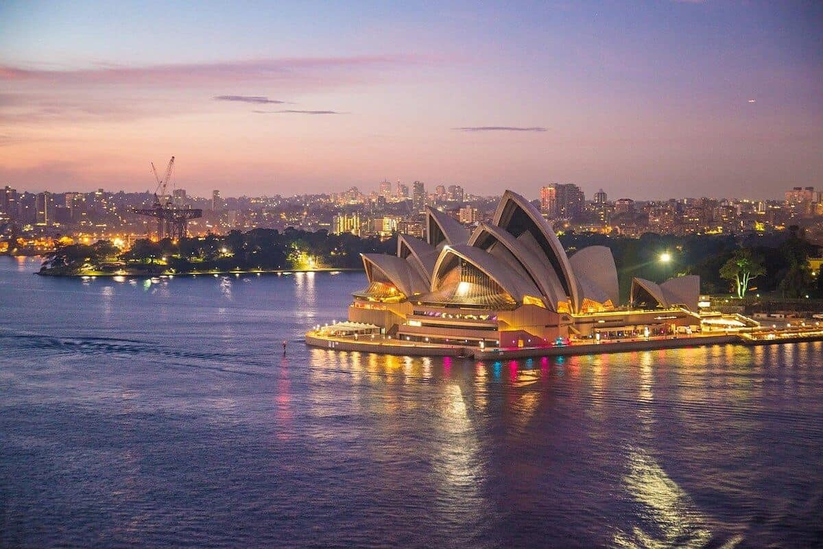 New South Wales Travel Guide Header Photo of Sydney Opera House at night, with a pink sky and purple looking water