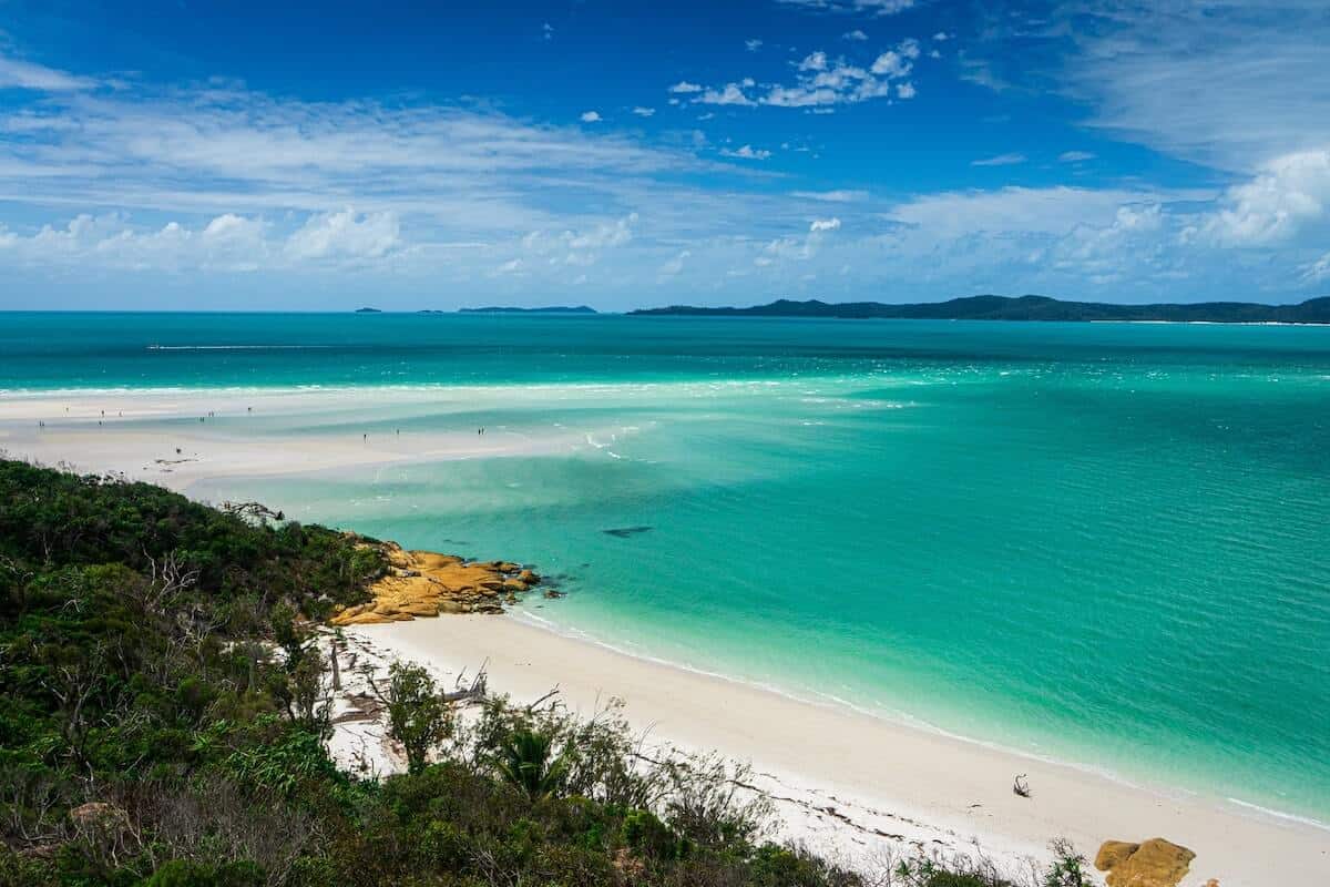 Queensland Travel Guide cover photo of an empty beach next to the clear blue ocean