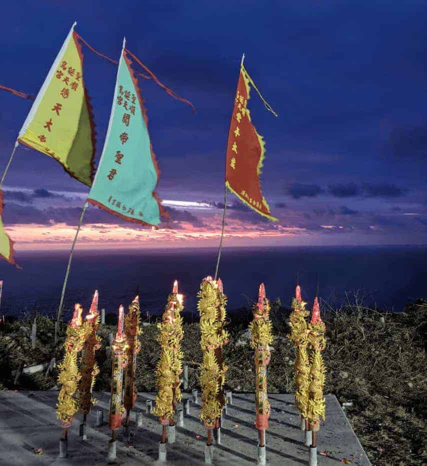 South Point Temple flags and religious celebration paraphernalia overlooking the ocean under the purple sky at dusk