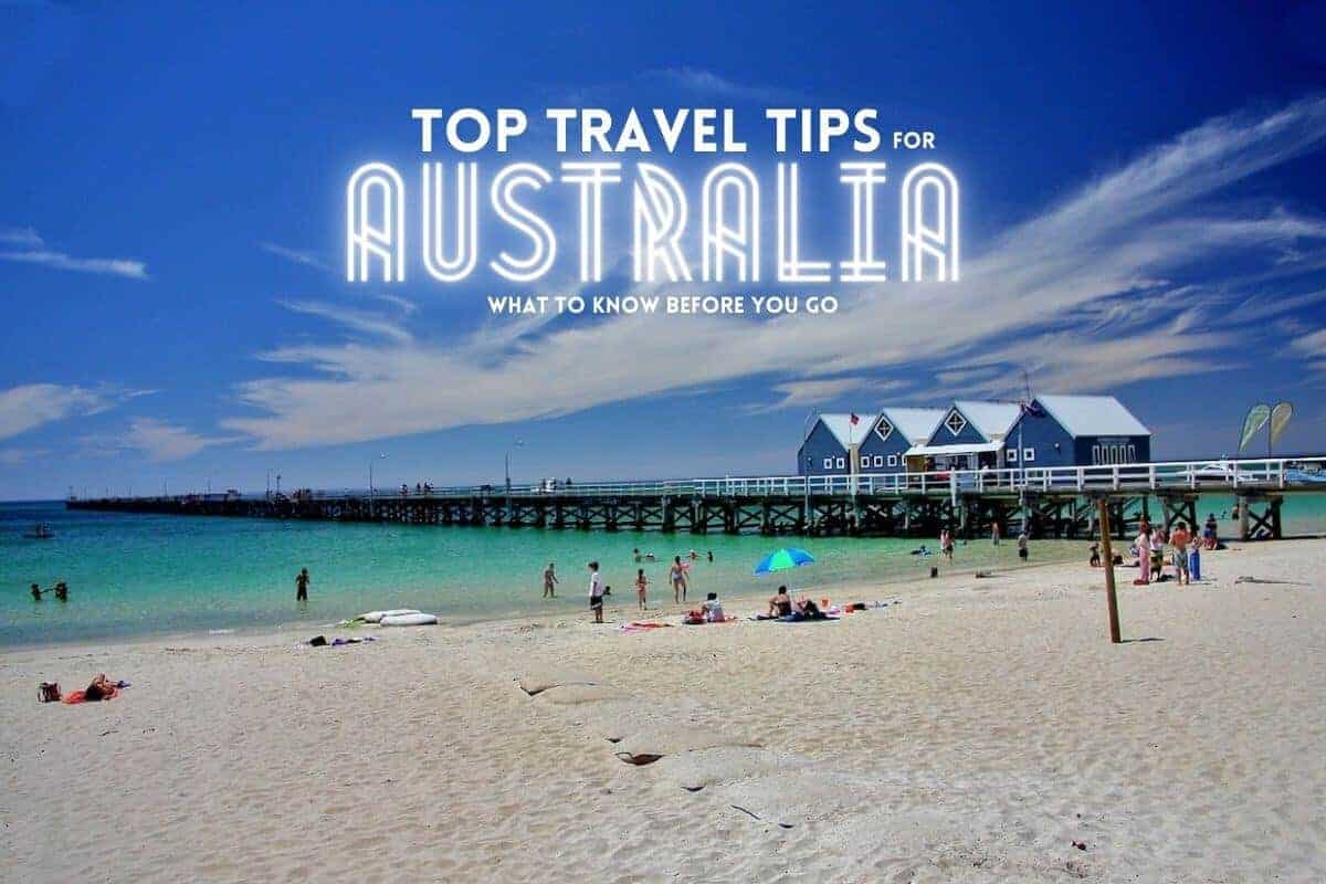 Top Travel Tips for Australia header image of Bussleton Beach with people sunbathing in front of the light blue ocean with the jetty in the background with 4 wooden beach huts on the jetty with text overlay stating 'top travel tips for Australia: what to know before you go'