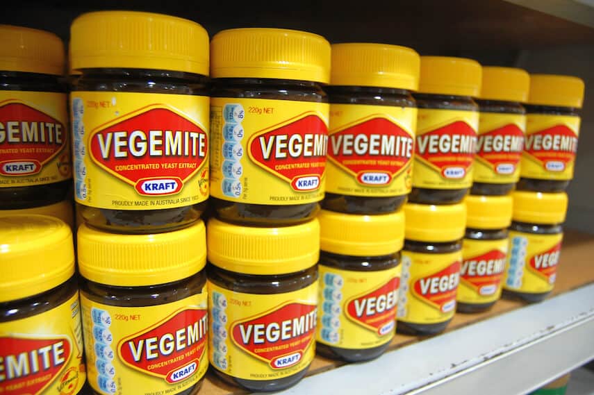 Yellow and Red tubs of Vegemite lined up on a shelf in the supermarket