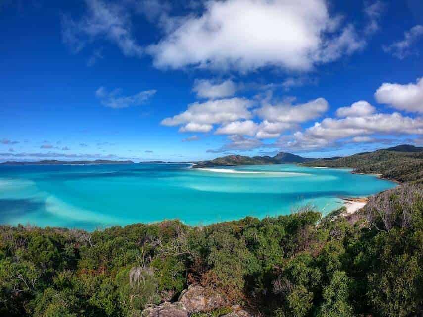 Whitsunday Islands - blue waters, white sand beach, green rainforest, blue skies and white fluffy clouds
