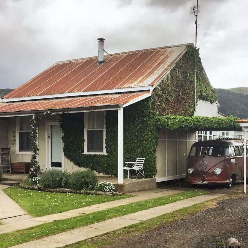 Exterior of Little Ivy Cottage with a battered and rusted VW campervan purked under the attached awning