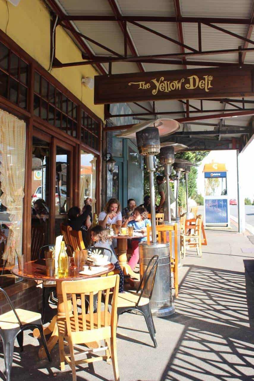 Outside the Yellow Deli cafe with tables and people outside under a wooden terrace