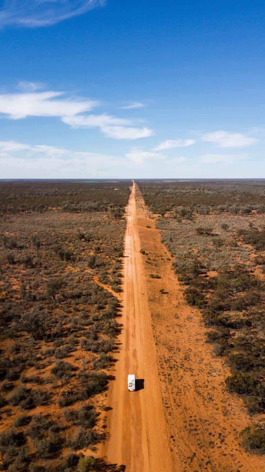 Red dirt road flanked by scrub and bush