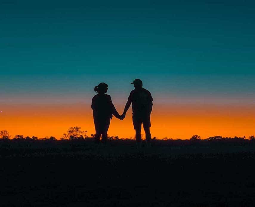 Couple holding hands in front of the sunset at Longreach in Outback QLD