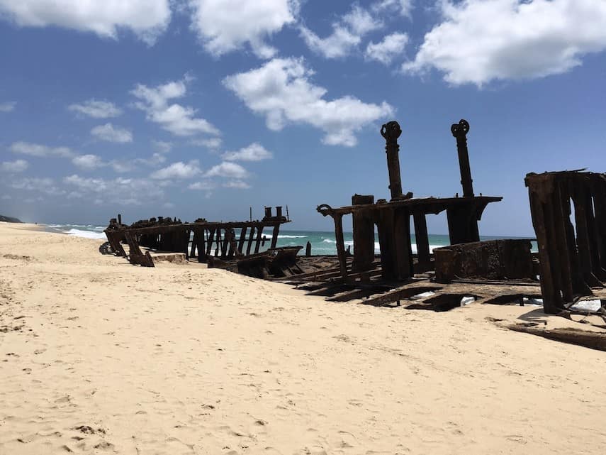 Shipwreck buried in the sand with the ocean in the background