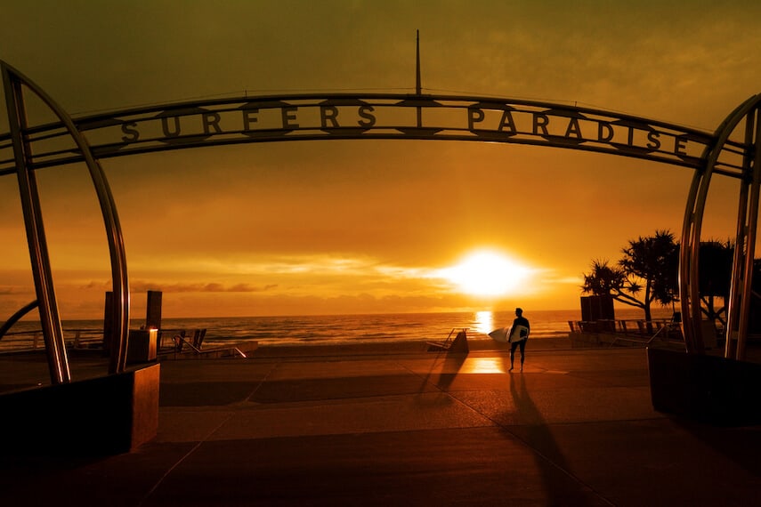 Surfers Paradise Silver Archway sign above the sand with the sunset in the background