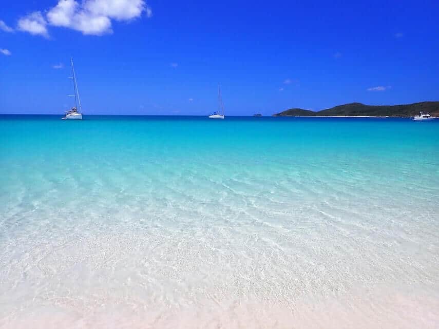 White sand with turquoise water and white yachts in the background at Whitehaven Beach, Whitsundays