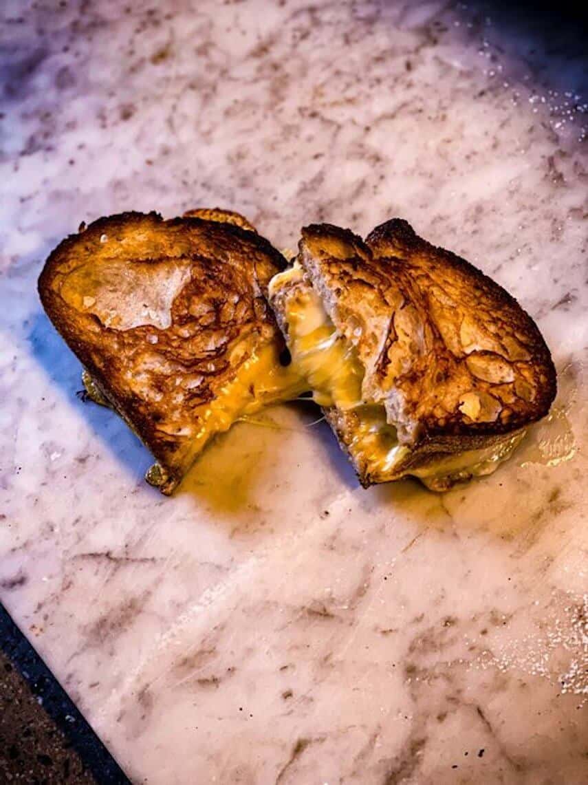 Toastie oozing with cheese cut in half on a marble table