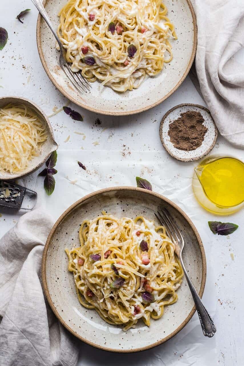 Top down shot of two plates of fettuchini pasta covered in a light cream sauce