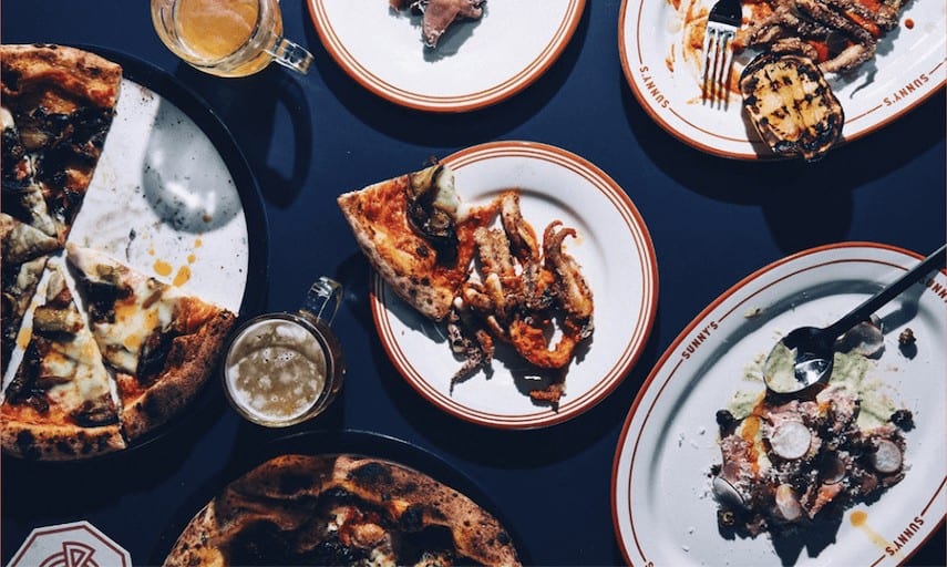 Top down shot of a large table with multiple different pizza and pasta dishes laid out