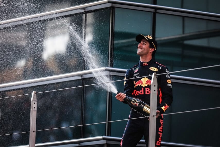 Daniel Riccardo in a Red Bull Racing Suit spraying champagne from a raised platform