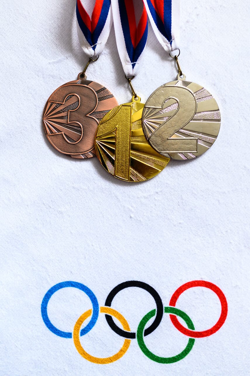Olympic Bronze, Silver and Gold medals on a white background, with the Olympic rings below