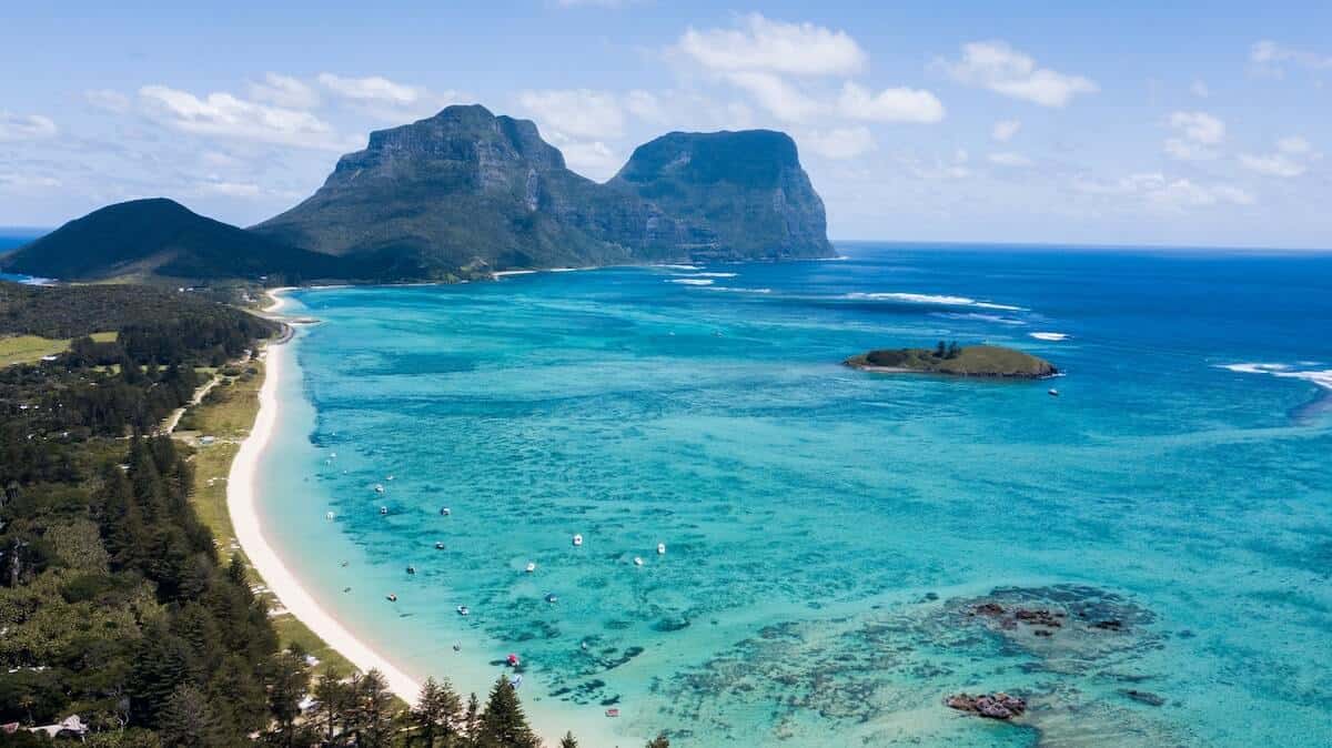 UNESCO World Heritage Sites in Australia cover photo of blue ocean along a long white sand beach on a tropical island