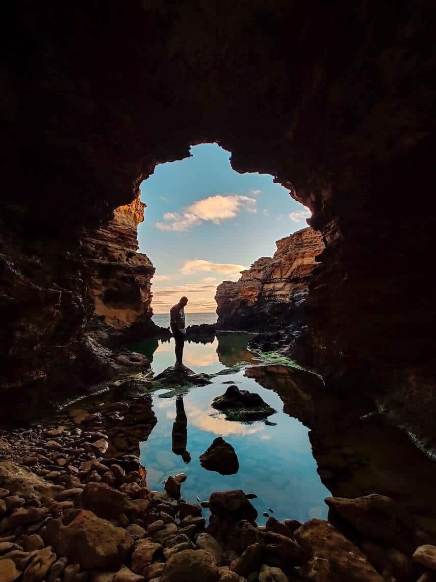 Man standing in a rock cave by the ocean at the Grotto on the Great Ocean Road